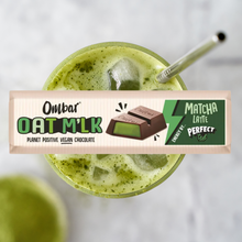Green matcha latte with a bar of Ombar Oatmilk chocolate on a white background