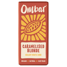 Red Ombar Caramelised Blonde creamy white chocolate bar wrapper, featuring a golden cacao pod and sunburst; labeled organic, natural, fair trade.