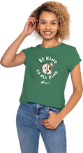 Woman wearing a green t-shirt with 'Be Kind To All Kind' text and a peace sign graphic.