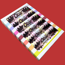 A box of six chocolate Catherine's Original Vegan Milk Chocolate O'bar bars sits on a red background, with colorful striped wrappers and bold lettering creating a playful, bright tone.