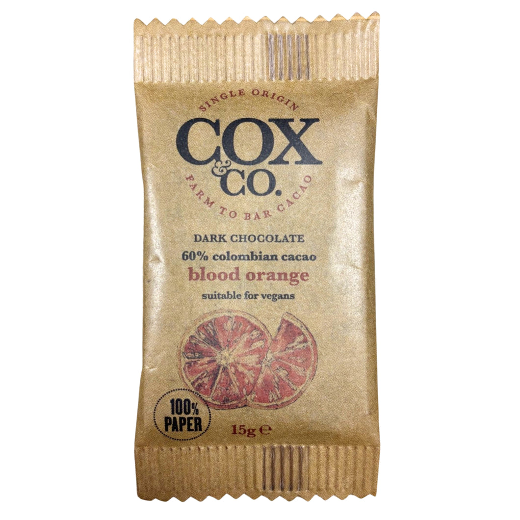 Gold Cox & Co. dark chocolate bar, labeled 60% Colombian cacao and blood orange; citrus illustrations and “100% paper” mark give it an artisanal feel.