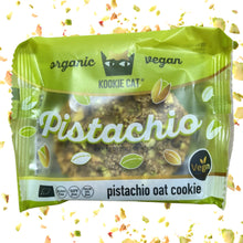 Green Cookie Cat vegan pistachio oat cookie wrapper, surrounded by scattered pistachio pieces; playful, fresh packaging highlights organic ingredients.